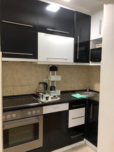 a kitchen with black and white cabinets and a sink at Apartman San Remo Brcko in Brčko