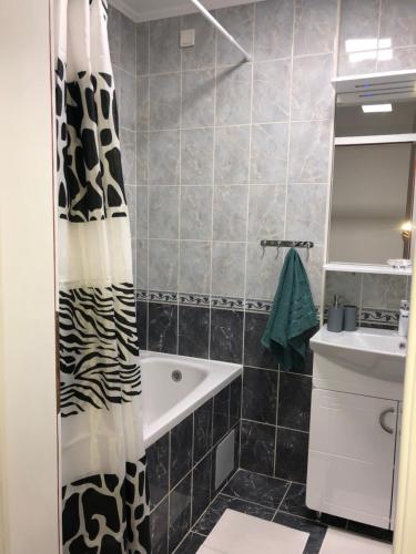 a bathroom with a black and white shower curtain and a sink at Apartman San Remo Brcko in Brčko