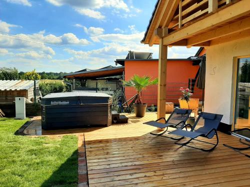 a backyard with a hot tub and two chairs on a deck at Landliebe, Luxus-Ferienhaus, 3 Schlafzimmer mit Sauna und Outdoor Whirlpool in Geierswalde