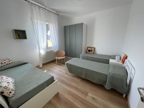 Un dormitorio con dos camas y una ventana. en Casa Tullo, en San Costanzo