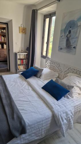 una camera da letto con un grande letto bianco con cuscini blu di Le Mas du Sud a Draguignan