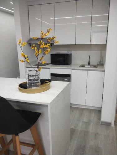 a kitchen with white cabinets and a vase with yellow flowers at Suite PRIVADA Torre D CCCT Caracas in Caracas