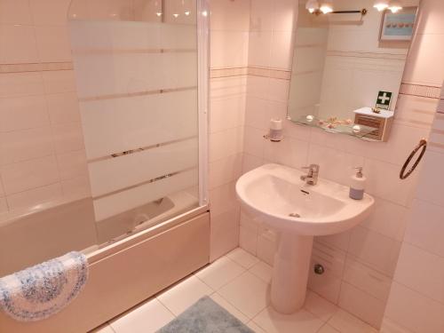 Un baño blanco con lavabo y ducha. en Verde Ria apartamento, en Torreira