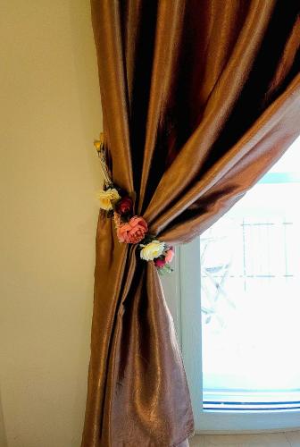 a brown curtain with flowers on it next to a window at B&B Donna Francè Pompei - Scafati in Scafati