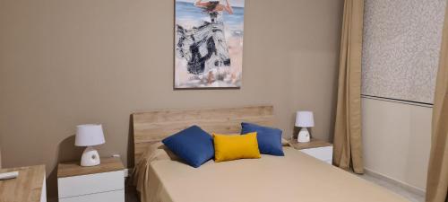 a bedroom with a bed with blue and yellow pillows at Large Apartment in Marsascala. sleeps 6 in Marsaskala