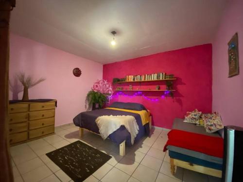 um quarto com uma parede rosa, uma cama e uma cómoda em Calli Tonanzin em Tepoztlán