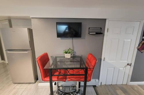 uma mesa com duas cadeiras vermelhas e uma televisão na parede em Cozy Adorable 2 bedroom Luxury Suite em Newark
