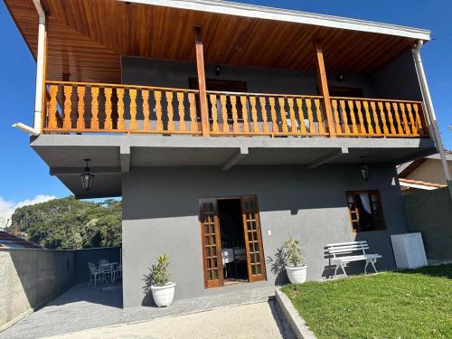 a house with a balcony with a deck at Raio de Sol na Montanha in Campos do Jordão