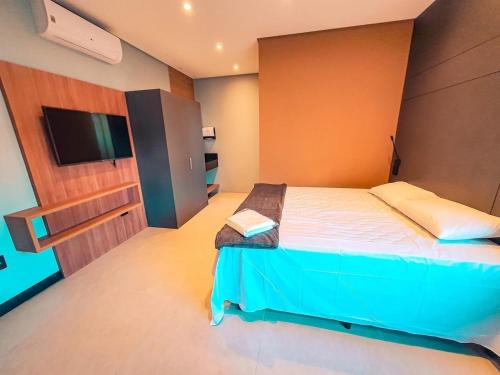 a bedroom with a bed and a flat screen tv at Globo Lar Studios in Limeira
