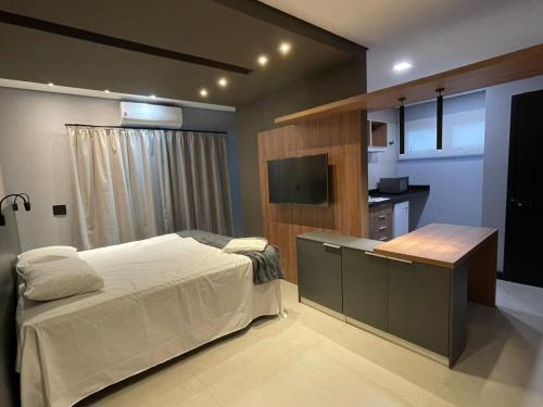 Dormitorio con cama, escritorio y TV en Globo Lar Studios, en Limeira