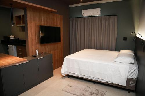 a bedroom with a bed and a flat screen tv at Globo Lar Studios in Limeira