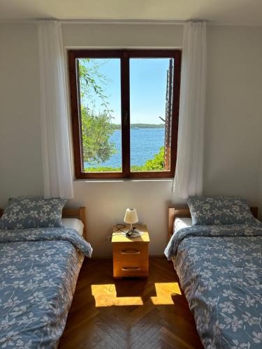a bedroom with two beds and a window at Villa Porthos in Hvar