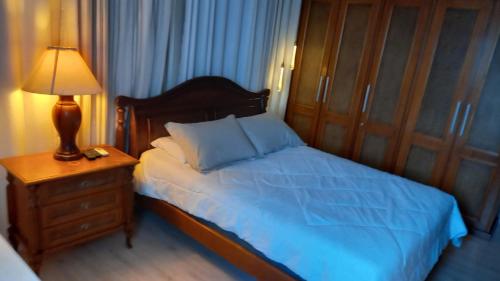 een slaapkamer met een bed met een nachtkastje en een lamp bij Casa chalé inteira gramado in Gramado