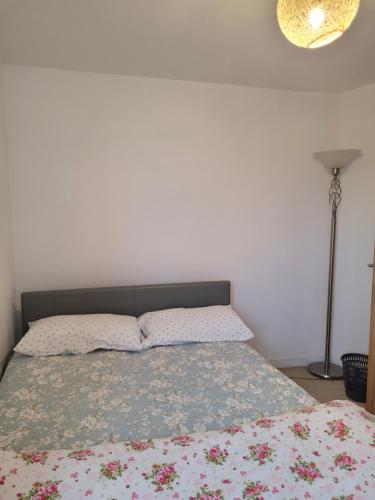 una camera da letto con un letto con copriletto floreale e una lampada di Room near Heathrow Airport a New Bedfont