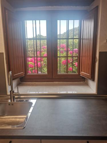 a kitchen with a window with a view of pink flowers at Casa Rural Erre Q Erre in Oreña