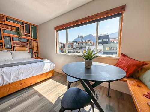 Schlafzimmer mit einem Bett, einem Tisch und einem Fenster in der Unterkunft Crash Hotel Squamish in Squamish