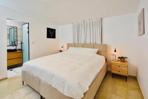 um quarto com uma grande cama branca e um espelho em אדמת הארץ - Admat Haaretz em H̱azon