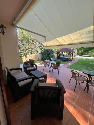a patio with tables and chairs and a gazebo at Aventurin House *** in Révfülöp