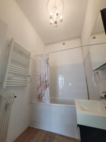 a bathroom with a tub and a sink and a chandelier at Appartement standing centre Gare LILLE FLANDRES in Lille