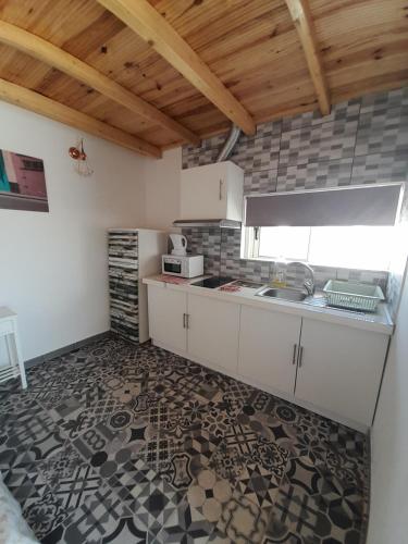 Una cocina con gabinetes blancos y piso de baldosas. en Estudio Dominicana in Albufeira Gale with garden and parking place, en Albufeira