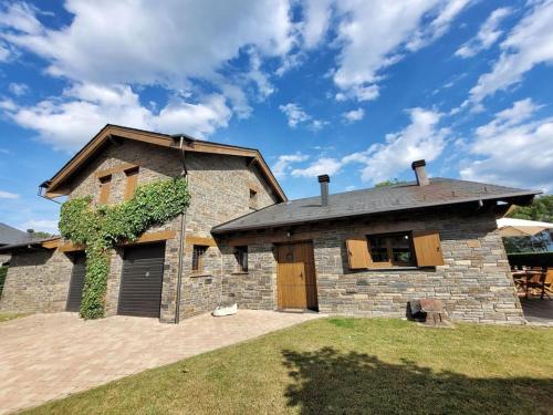 een stenen huis met een dak met een tuin bij El Xalet de la Padrille in Enveitg