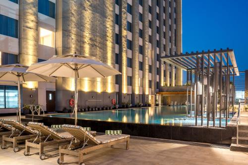 a pool in a building with chairs and umbrellas at Holiday Inn Lucknow Airport by IHG in Lucknow