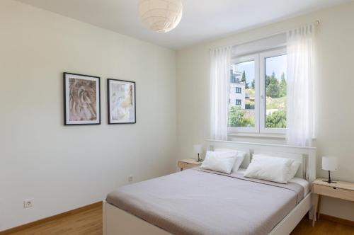 een witte slaapkamer met een bed en een raam bij Flora Luxury Apartment in Dubrovnik