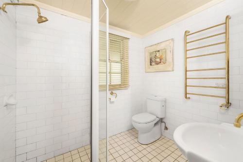 La salle de bains blanche est pourvue de toilettes et d'un lavabo. dans l'établissement Eco Cottage Alpine Southern Highlands, à Alpine
