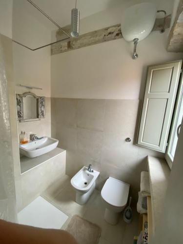 La salle de bains blanche est pourvue de toilettes et d'un lavabo. dans l'établissement Casa Opera, à SantʼAntìoco