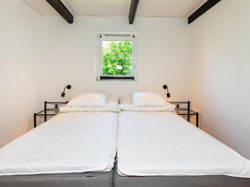 a bedroom with a large white bed with a window at Holiday home Løgstør IX in Løgstør