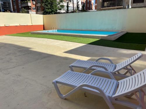 two white benches sitting next to a swimming pool at BEST FLAT NEAR REAL MADRID STADIUM in Madrid