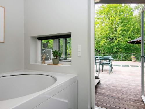a white bathroom with a tub and a patio at 8 person holiday home in Ebeltoft in Ebeltoft