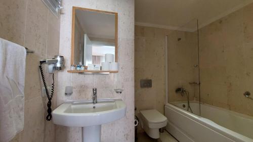 een badkamer met een wastafel, een toilet en een spiegel bij CLC Wyndham Kuşadası Golf resort in Soke