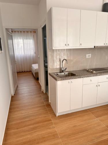 una cucina con armadietti bianchi e pavimenti in legno di Vila SUN 2E a Ksamil