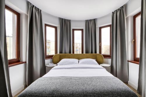 1 dormitorio con 1 cama grande y ventanas en Masuria Apartments, en Giżycko