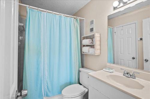 a bathroom with a blue shower curtain and a toilet at Holiday Surf and Racquet Unit 520 in Destin
