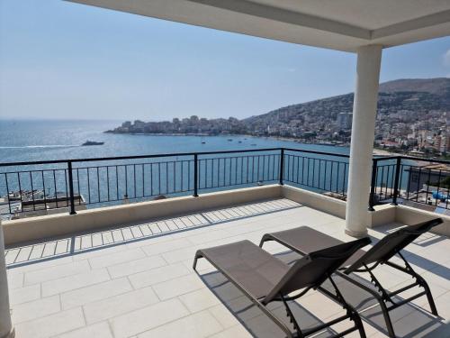 a balcony with two chairs and a view of the water at Joanna Suites in Sarandë