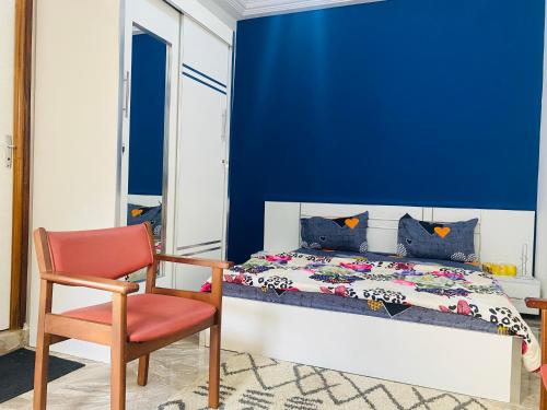 1 dormitorio azul con 1 cama y 1 silla roja en RESIDENCE EL HADJI, en Dakar