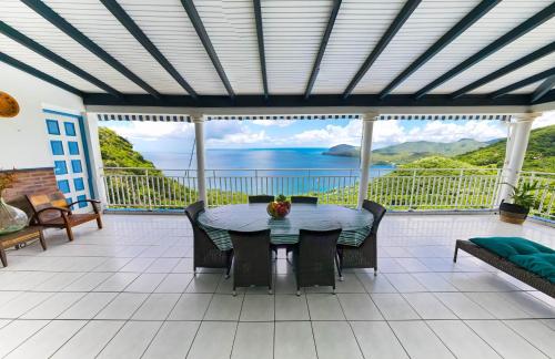 a patio with a table and chairs and a view of the ocean at Résidence La Clément in Les Anses-dʼArlets