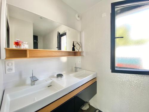 ein Bad mit einem weißen Waschbecken und einem Fenster in der Unterkunft LA VILLA PALMIER - Plages à 5 min in Concarneau