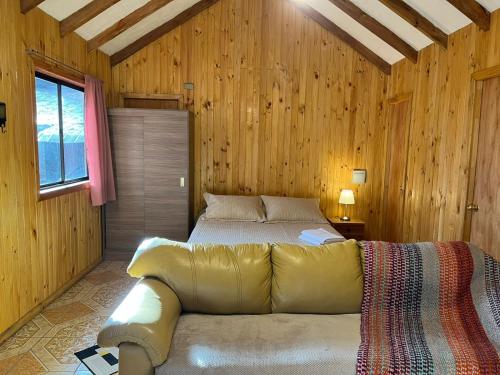 a bedroom with a bed with a couch in it at Cabañas Bosque las Trancas in Las Trancas