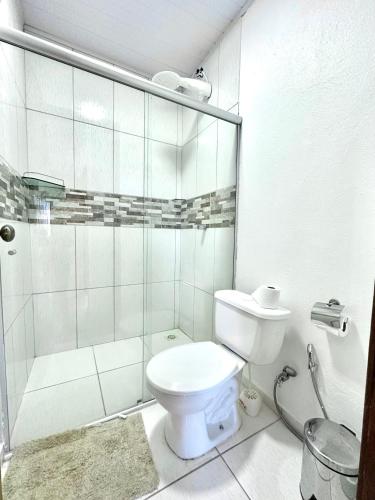 a bathroom with a toilet and a glass shower at Pousada/Camping Mirante Serrano in Alto Paraíso de Goiás