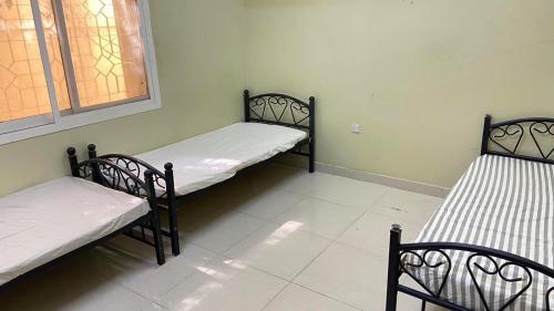 three beds in a room with a window at Al Jahili Sharing Rooms in Al 'Ayn