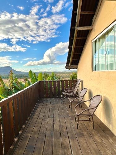 a deck with chairs and a view of the mountains at Pousada/Camping Mirante Serrano in Alto Paraíso de Goiás