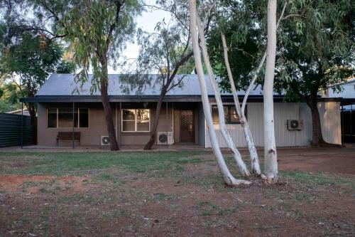 4 Bedrooms, 2 Bathrooms in Alice Springs في ينابيع أليس: منزل أمامه مجموعة من الأشجار