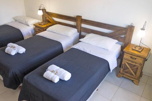 a hotel room with three beds with towels on them at Tranqueras Lodge in El Chalten