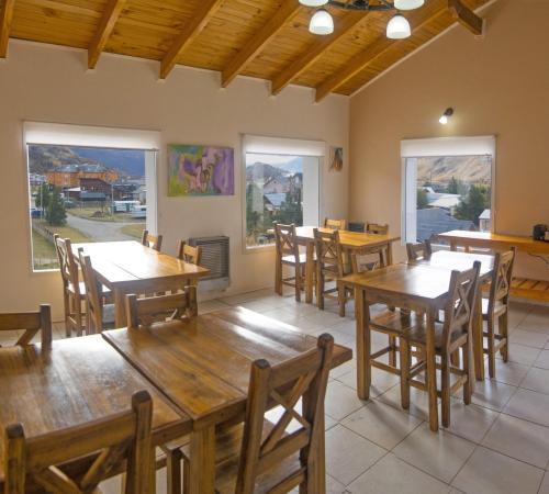 a restaurant with wooden tables and chairs and windows at Tranqueras Lodge in El Chalten