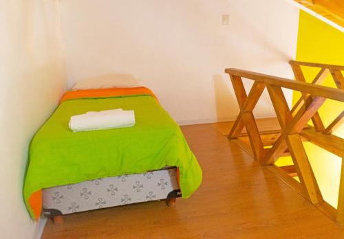 a small bed in a room with a green blanket at Tranqueras Lodge in El Chalten