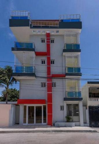 un edificio blanco alto con una raya roja. en Hotel La Playa, en Santa Cruz de Barahona