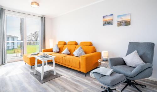 a living room with an orange couch and two chairs at Apartment "Sanddorn" - Haffresidenz in Garz-Usedom
